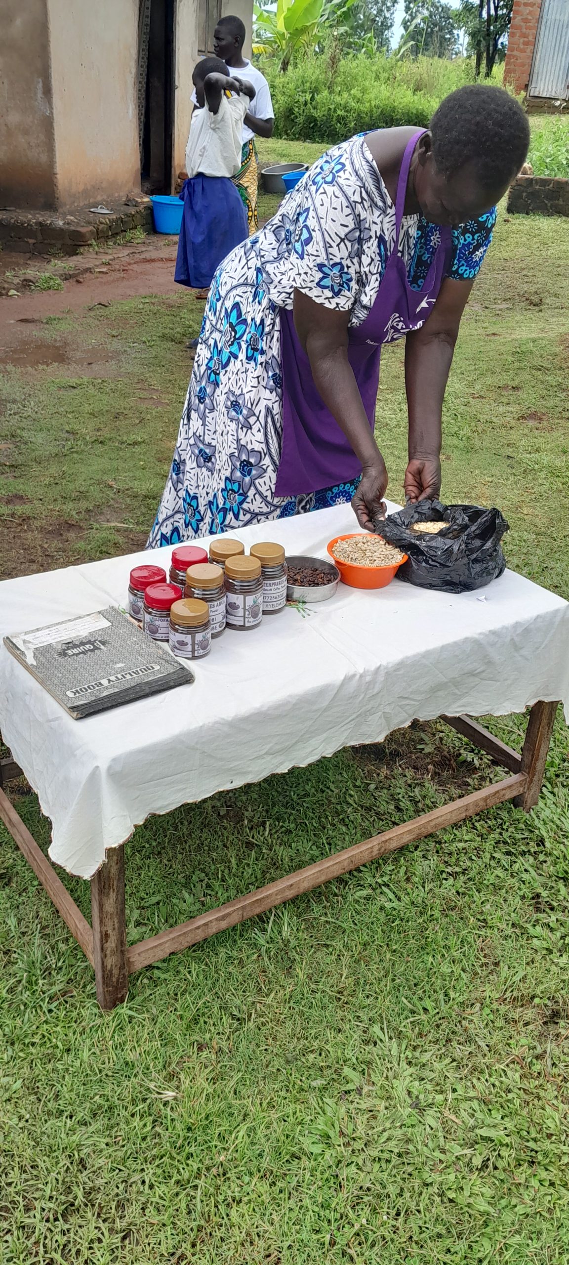 A woman arranges jars of processed produce on a display table